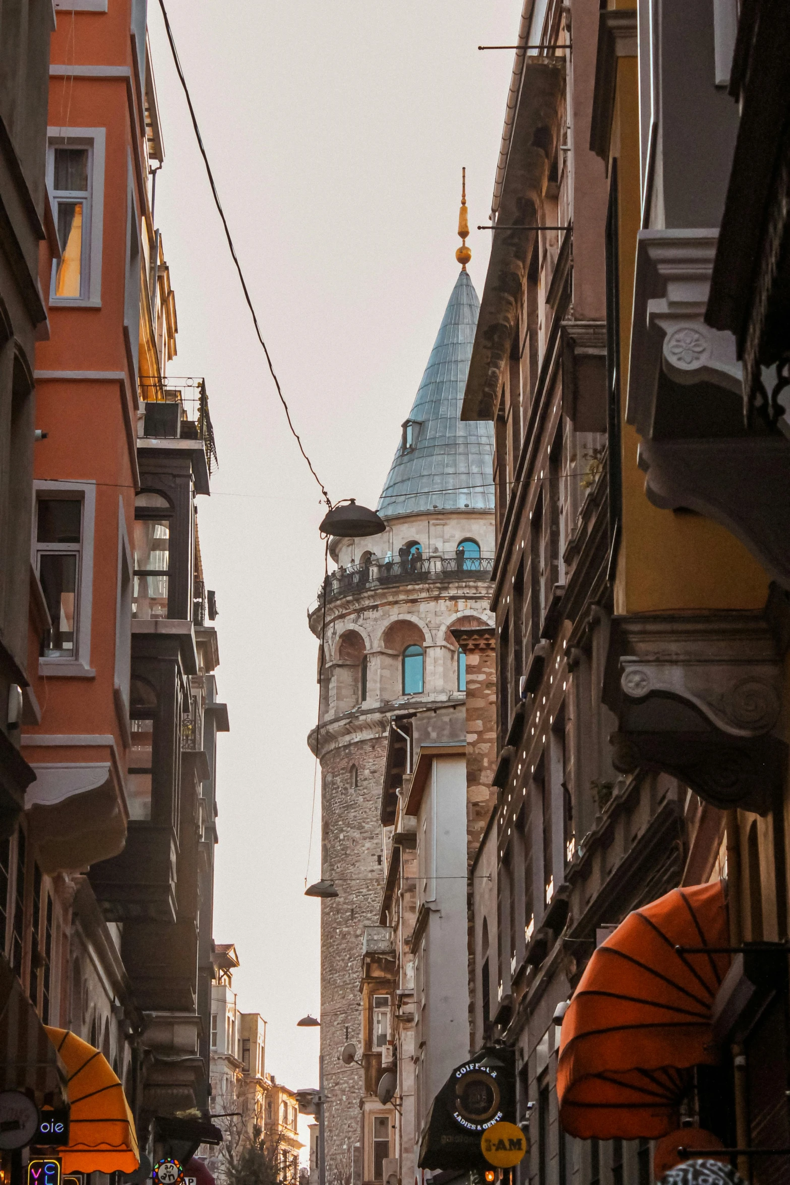 a narrow street with a building and umbrellas on both sides