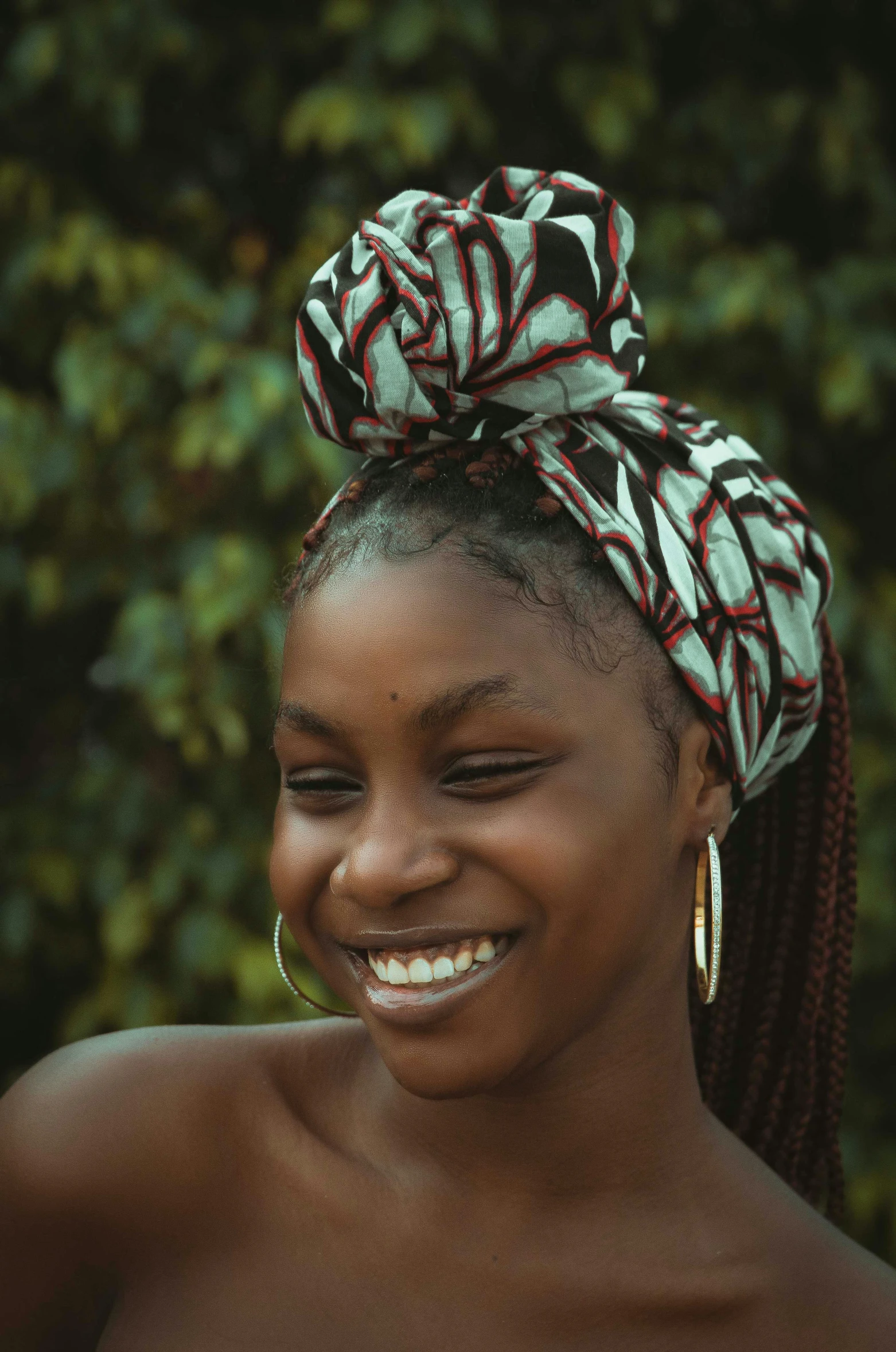 a woman smiles and wears a knoted head wrap