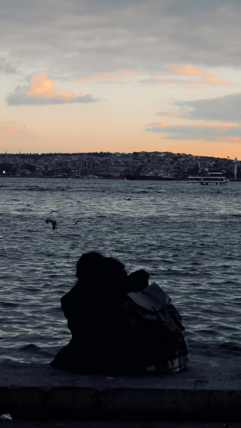 a person in front of water with birds flying over