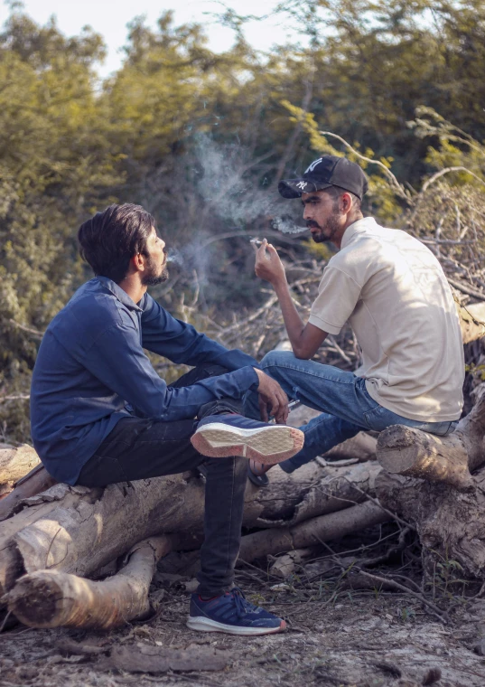 a man sitting next to another man, while he smokes soing