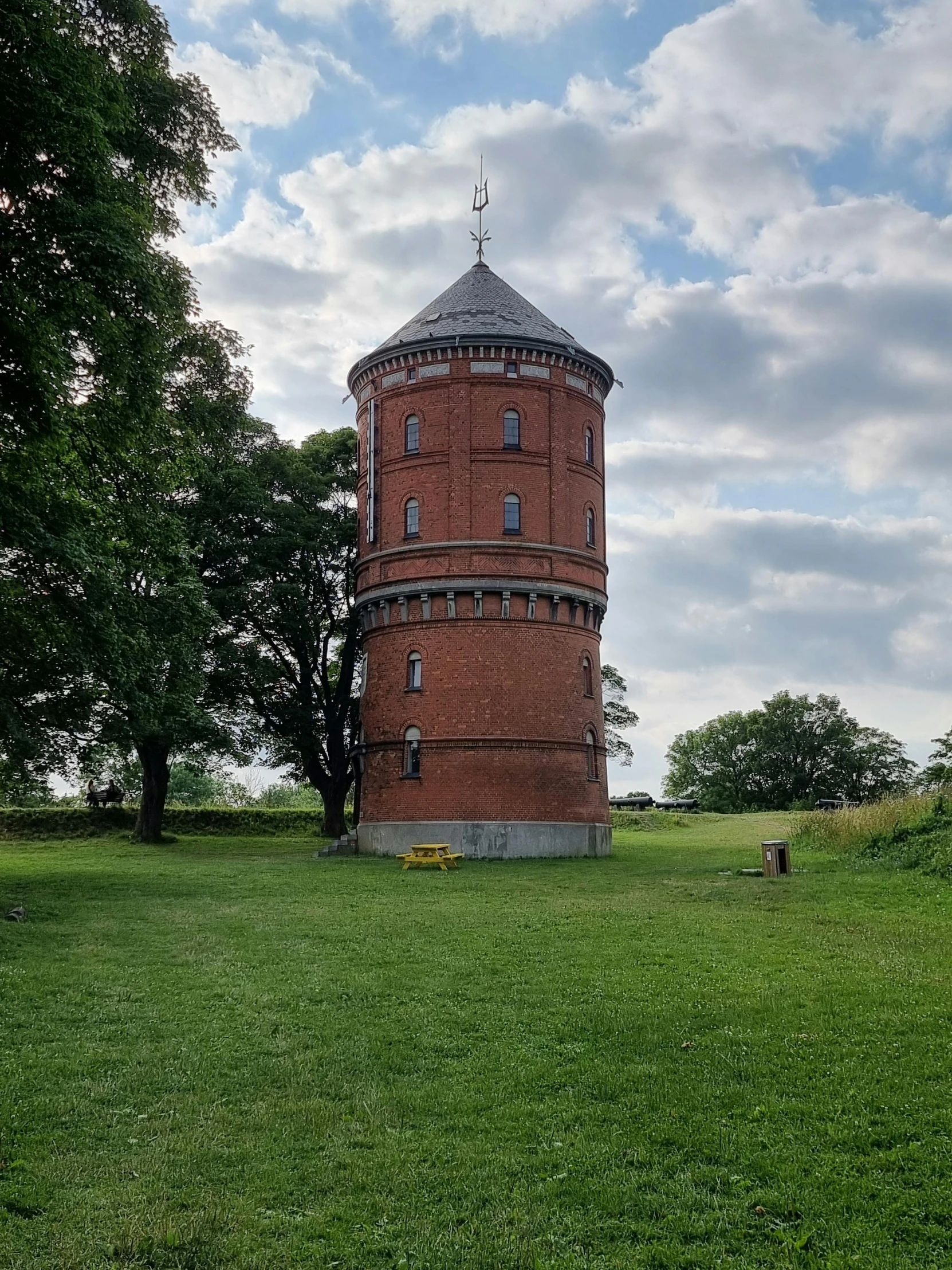 the circular brick building stands on the hill in a park