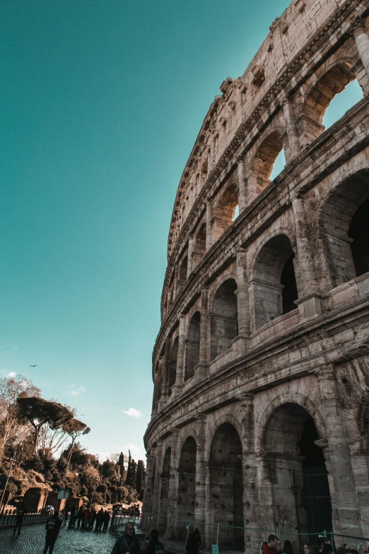 people walking along side of an old building under a blue sky