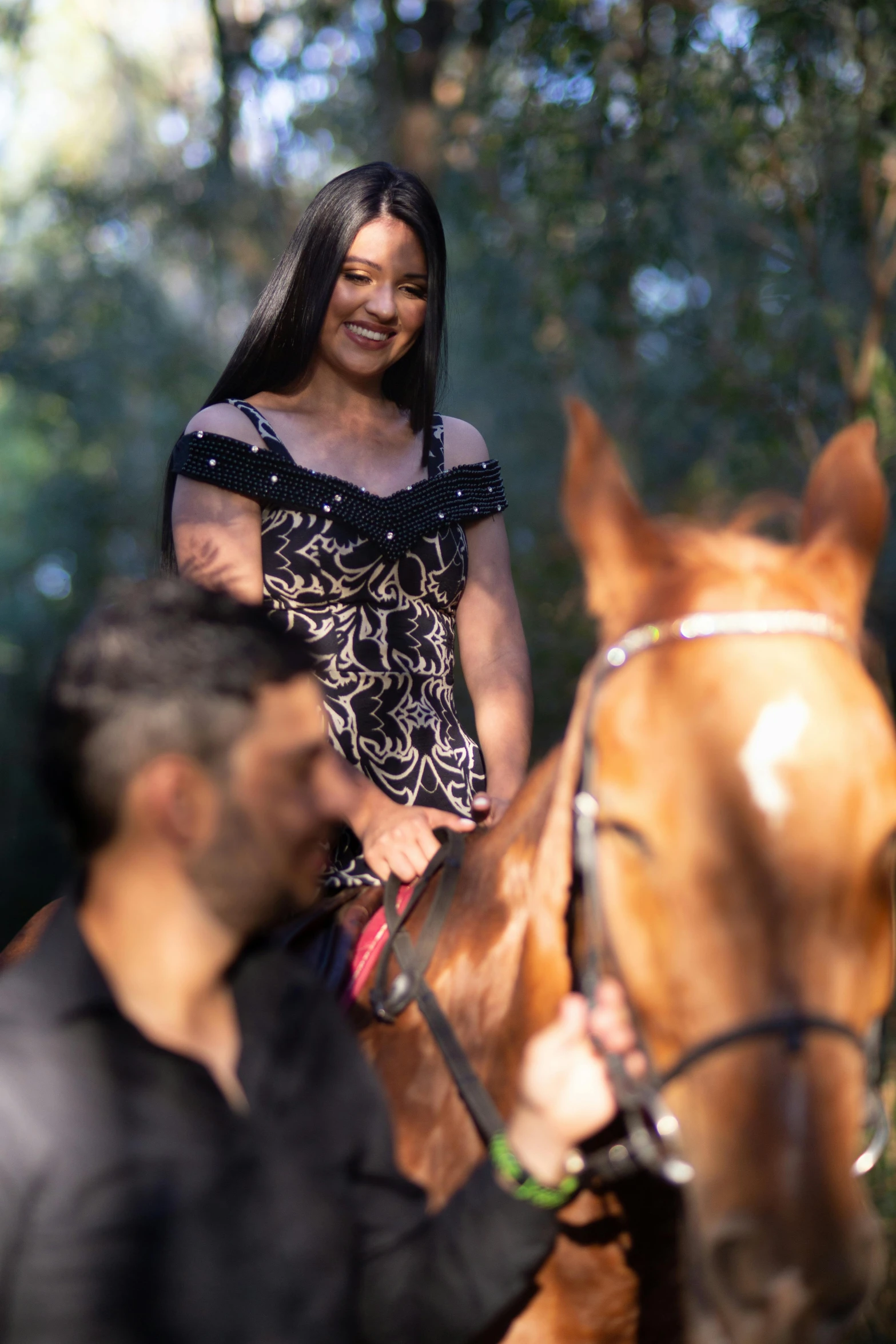 two men working with a smiling young lady on horseback