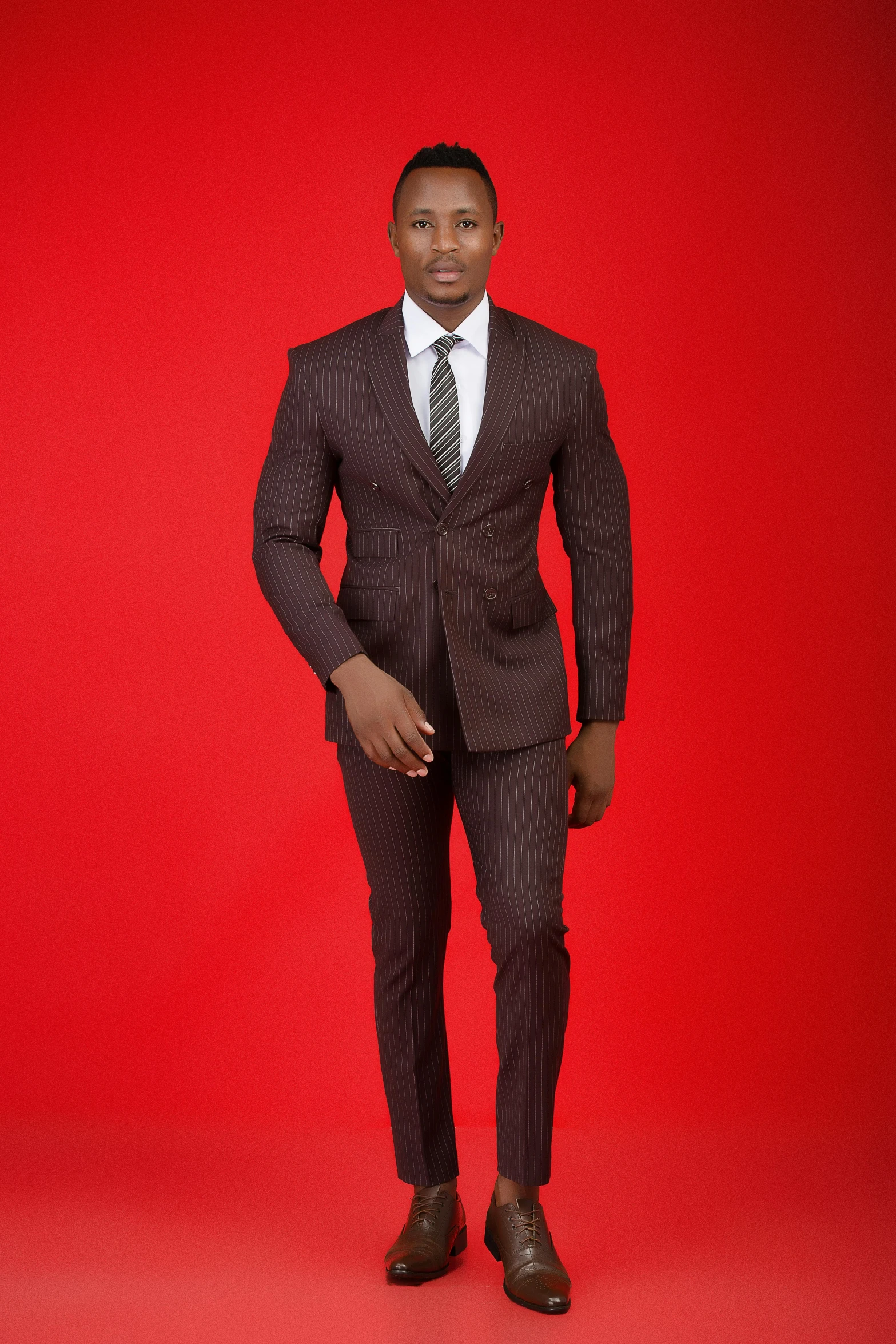 a person wearing a suit and tie stands in front of a red background