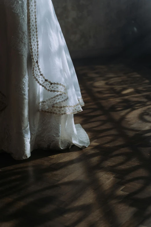 a woman's dress on a wooden floor with shadows