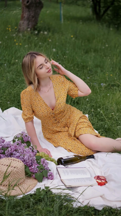 a woman sitting on top of a blanket next to purple flowers