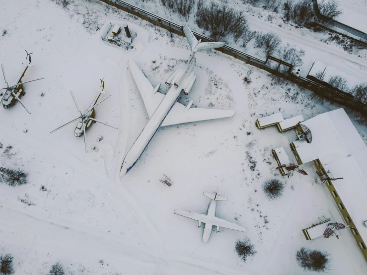 two airplanes in the middle of an airport covered in snow