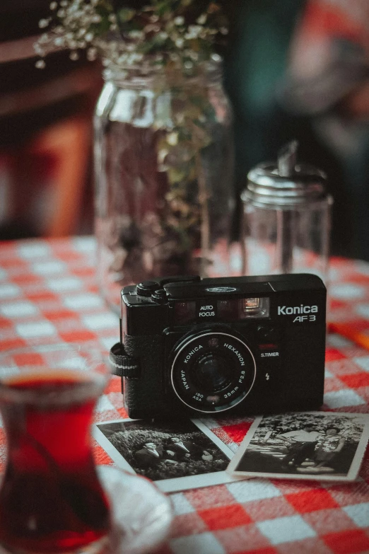 a compact camera sits on a red and white checkered tablecloth