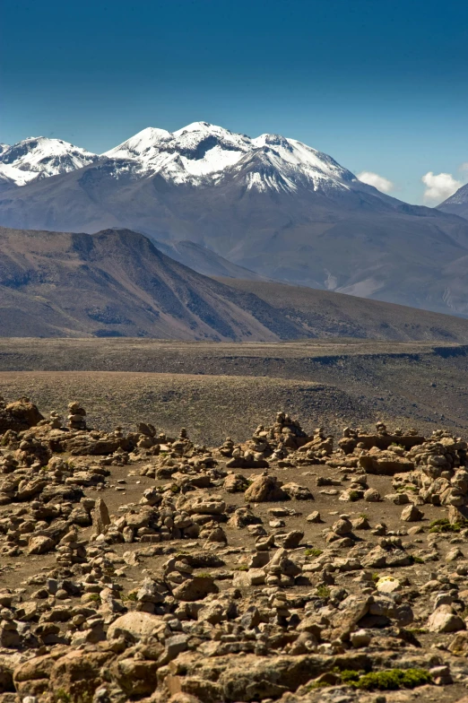 snow capped mountain in the distance with rocks and boulders on the foreground