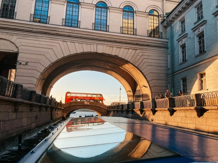 the sun is setting over a canal under a bridge