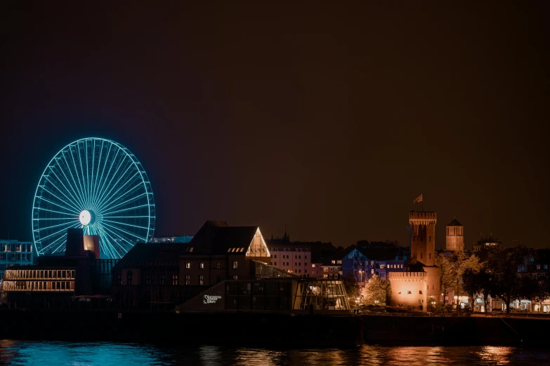 a ferris wheel is lit up on the river at night