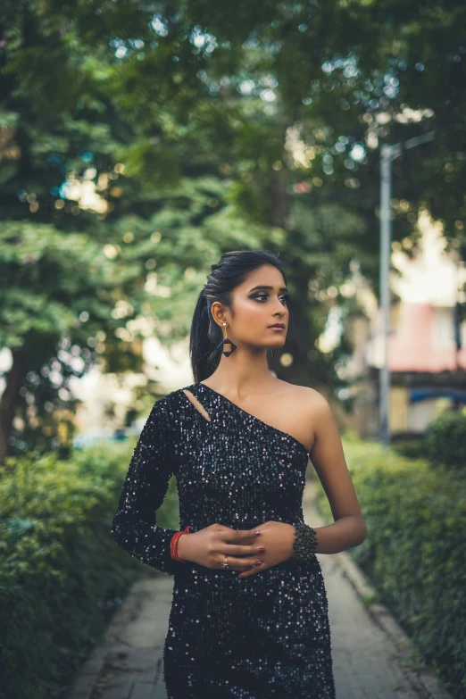 a beautiful woman standing on the sidewalk in front of trees