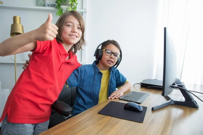 two children in office setting showing thumbs up