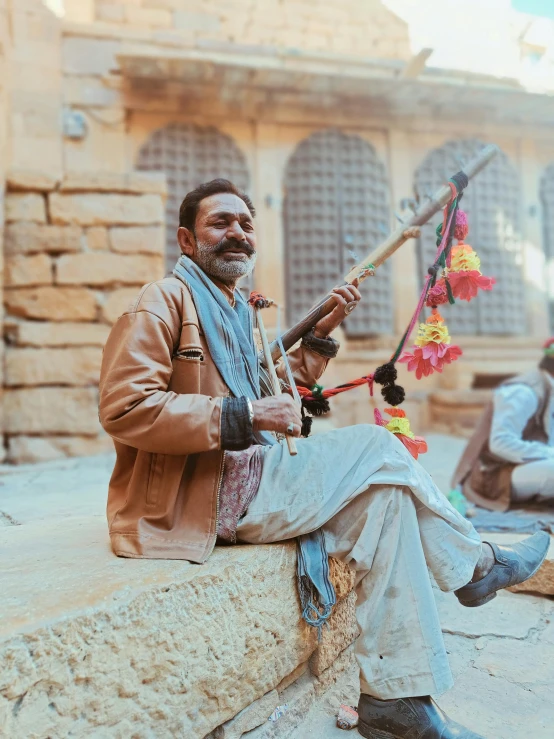 a man sitting in front of a house holding a pipe