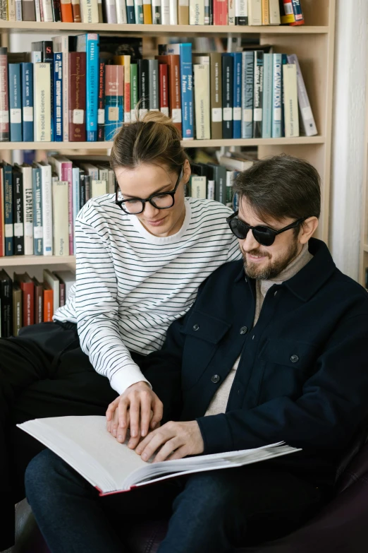 man and woman sit in front of bookshelves