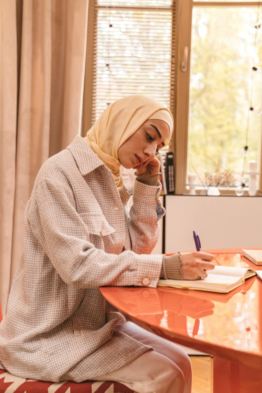 a woman with head turban writing and talking on a cell phone