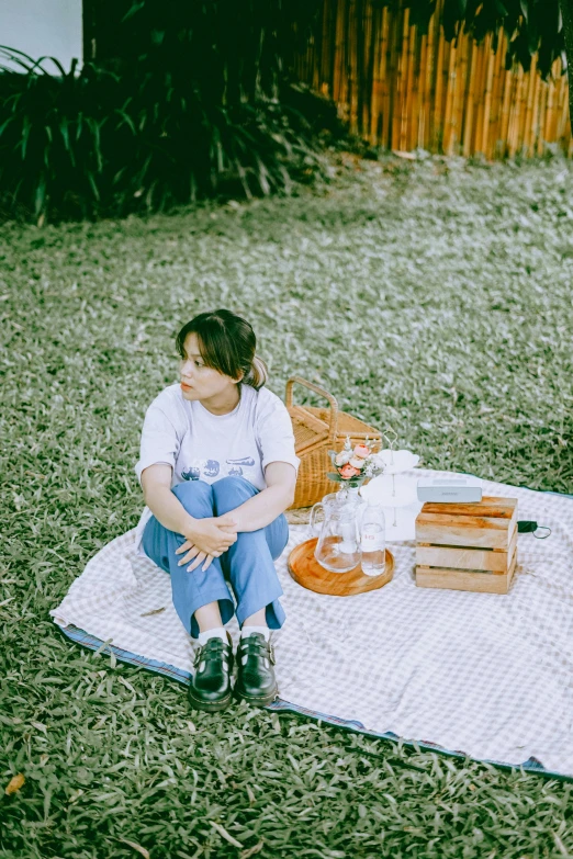 a woman sitting on a blanket near a picnic table