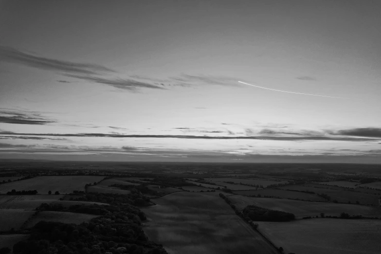 a plane flies in the sky over a plain