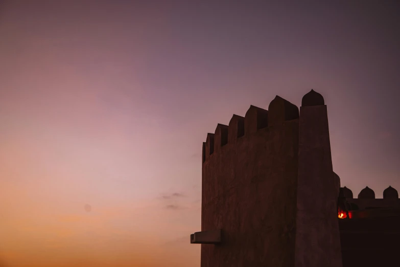 a silhouetted building in the dusk with a light post in front of it