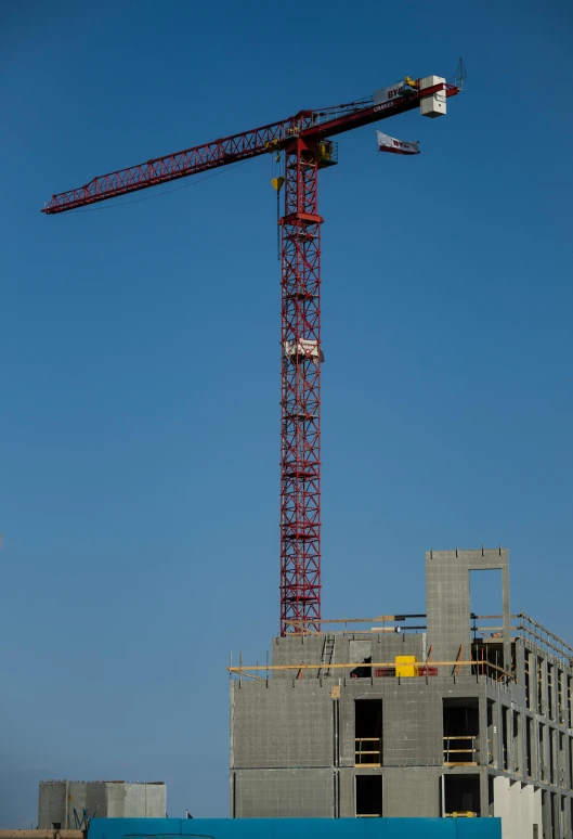 a tall crane standing in front of a building under construction