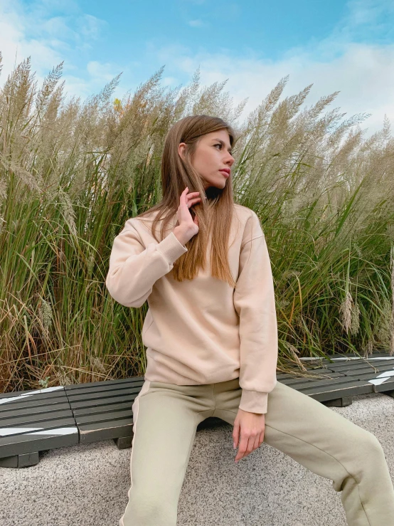 a woman wearing a sweater sitting in front of a plant