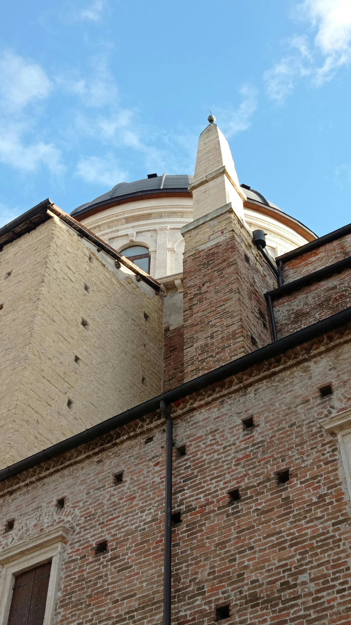 the side of a brick building with a very large round tower