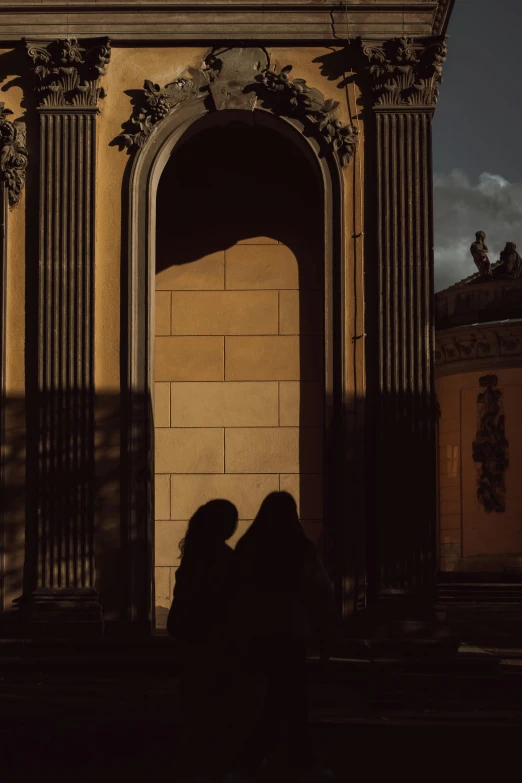 two people are silhouetted against the arch on a wall