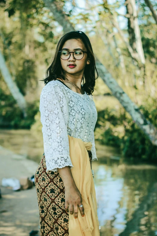 a girl in a yellow skirt standing next to a river