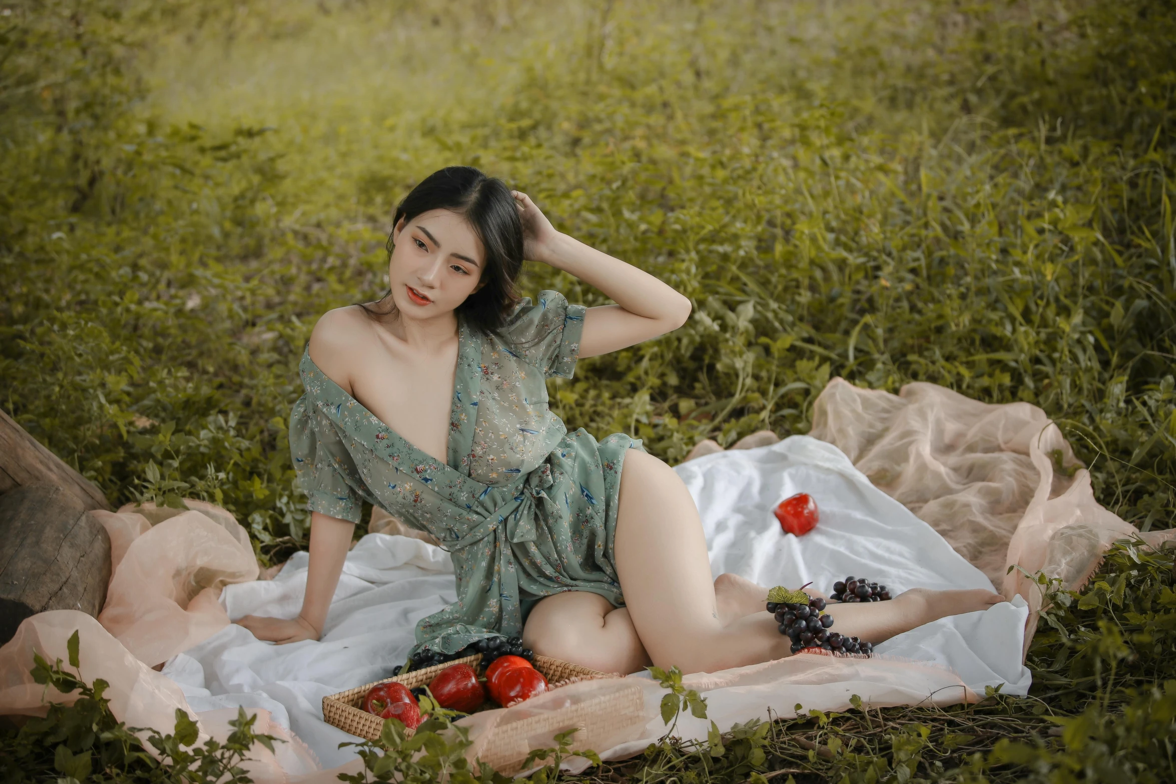 a woman in a green dress sitting on a blanket in a field