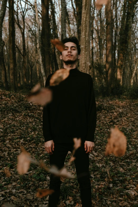 a man is standing in leaves while holding his head