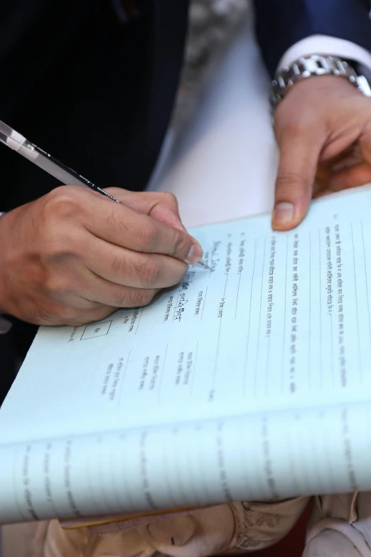 a man with a pen writing on top of a piece of paper