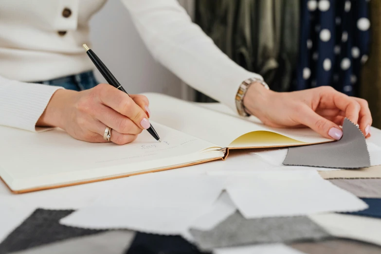 a hand holds a pencil while writing on a notebook