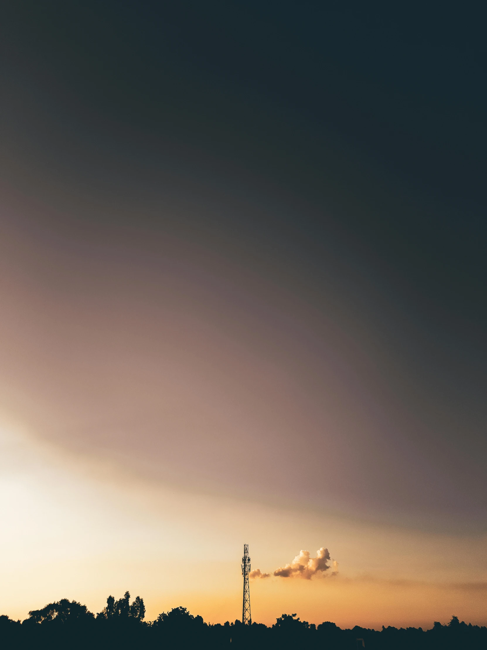 a bright yellow, orange and black sunset with the sun peeking through dark clouds