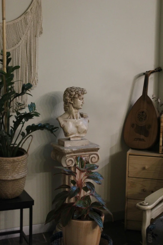 a busturine in a room with a guitar and a potted plant