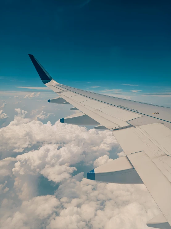 a plane flying through the blue sky above the clouds