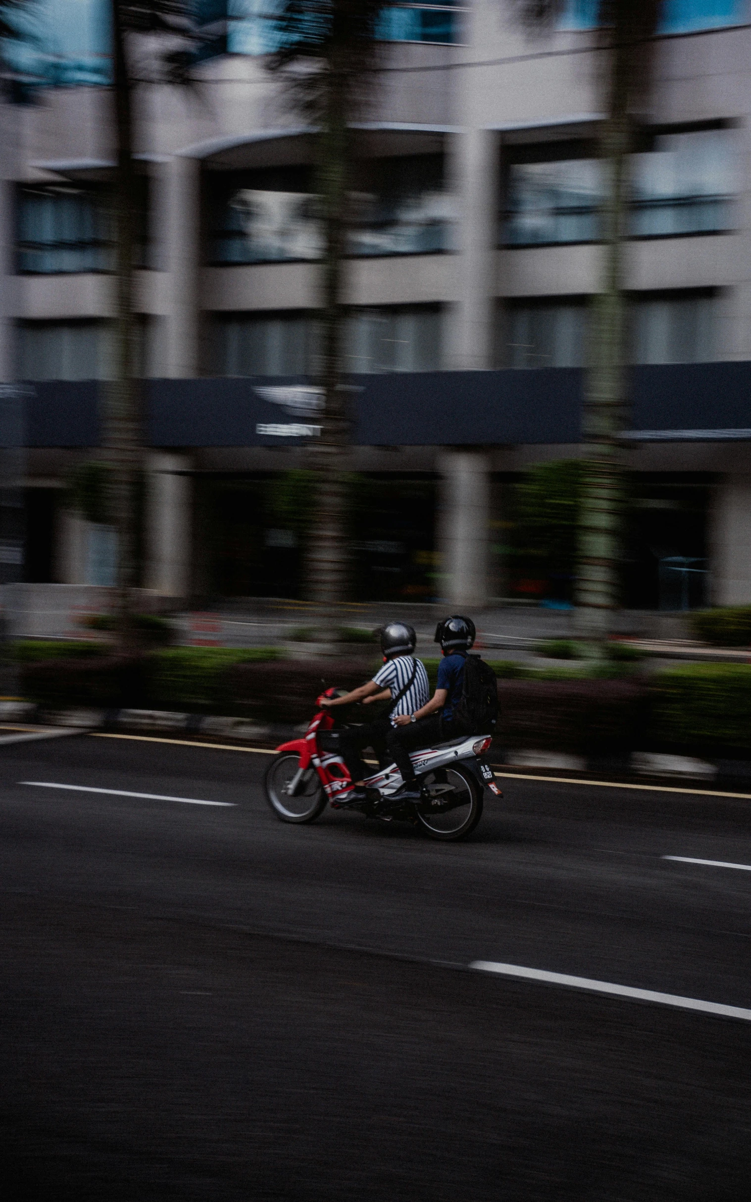 two people ride on a motor bike down the street