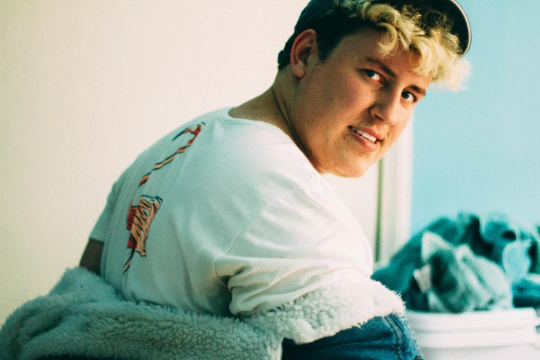 a young man poses for a pograph in a white shirt