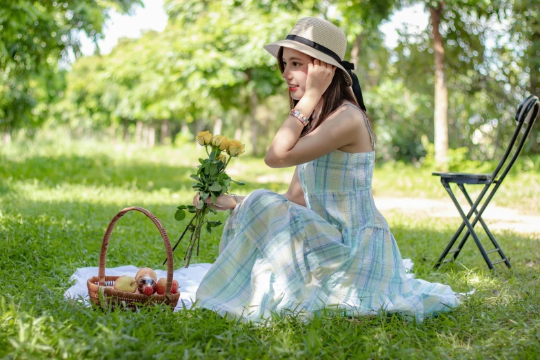 a girl in dress sitting on a blanket outside with flowers