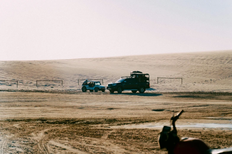 two pickup trucks driving along a dirt road