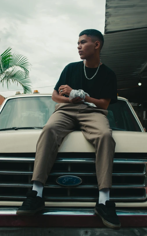 a young man sitting on the hood of his truck