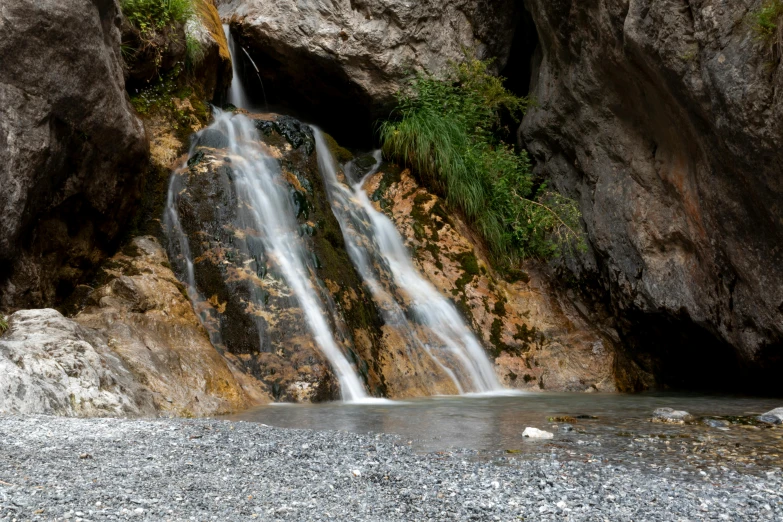 a waterfall with large rocks near by and some water