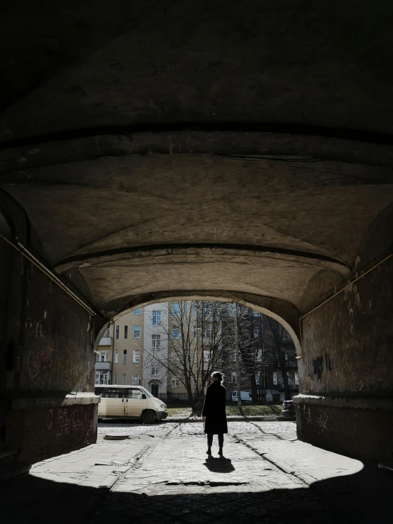 person in a tunnel on a street with buildings behind