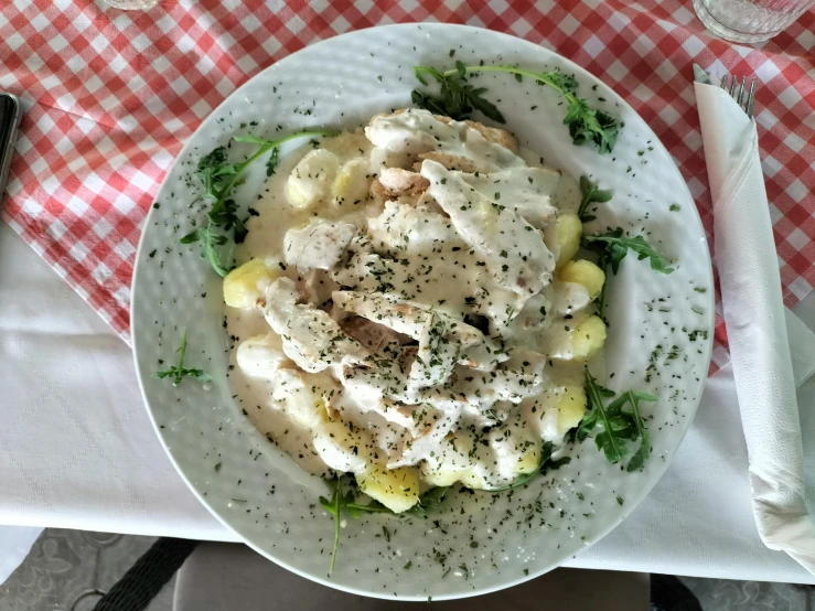 a bowl of chicken, mashed potatoes and spinach on a checkered tablecloth
