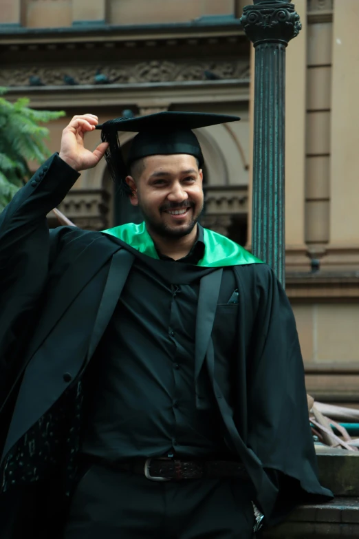 the man is posing with his graduation gown on