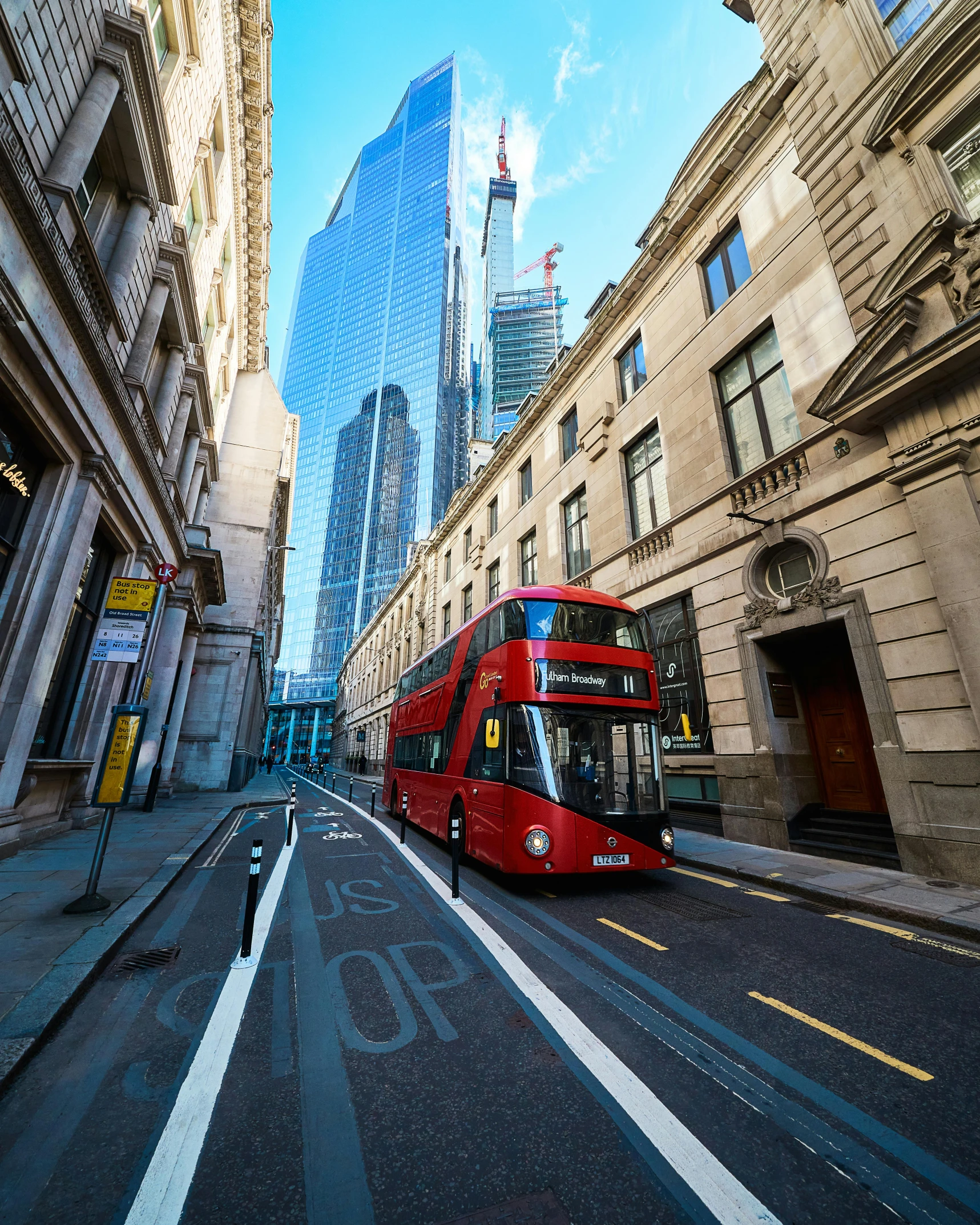 a double decker bus on a street with tall buildings in the background