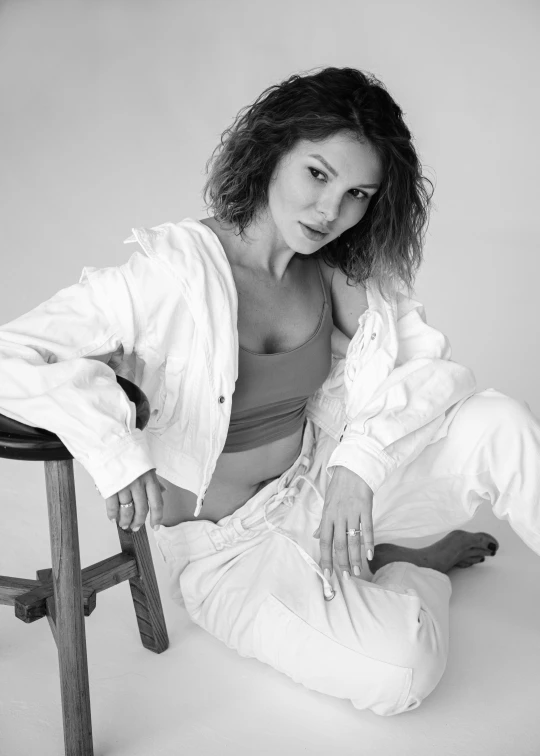 a woman sitting on top of a stool wearing all white