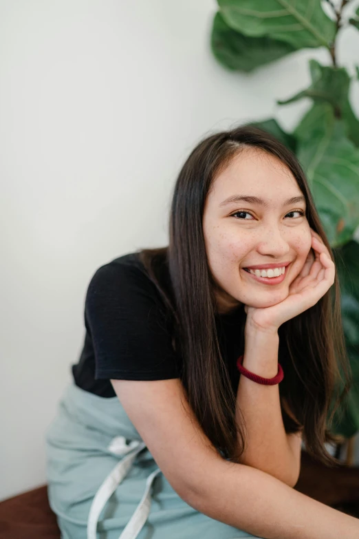 the girl is sitting down in front of a plant