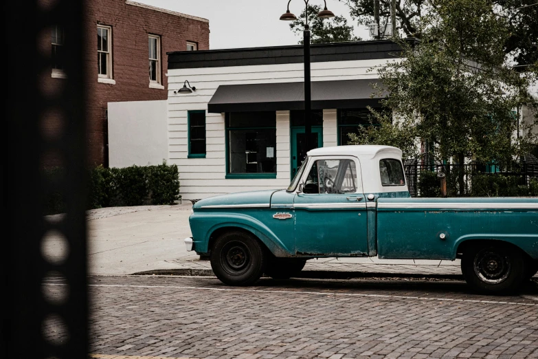an old fashioned green truck is parked on a street
