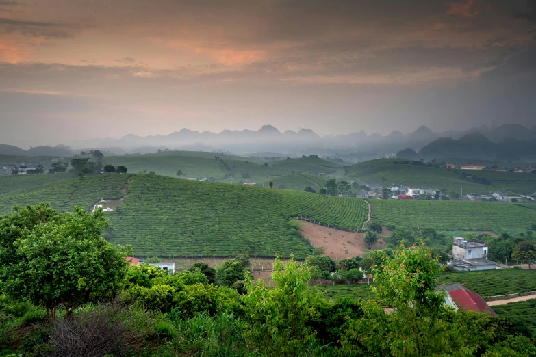 a valley filled with green hills under a cloudy sky