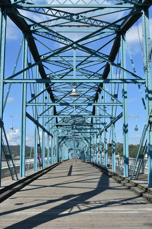 a blue metal bridge over a city river